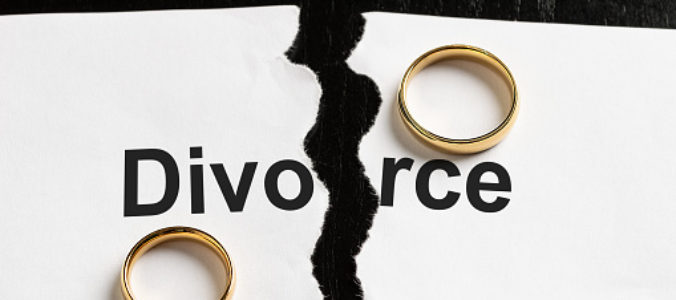 Closeup of a break document with the word divorce and two wedding rings